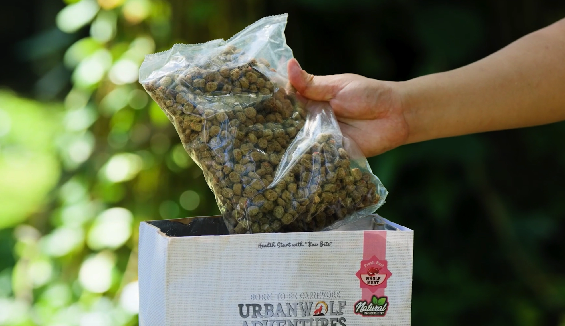 Pouring Urbanwolf Adventures Rawbarf kibbles into the bag